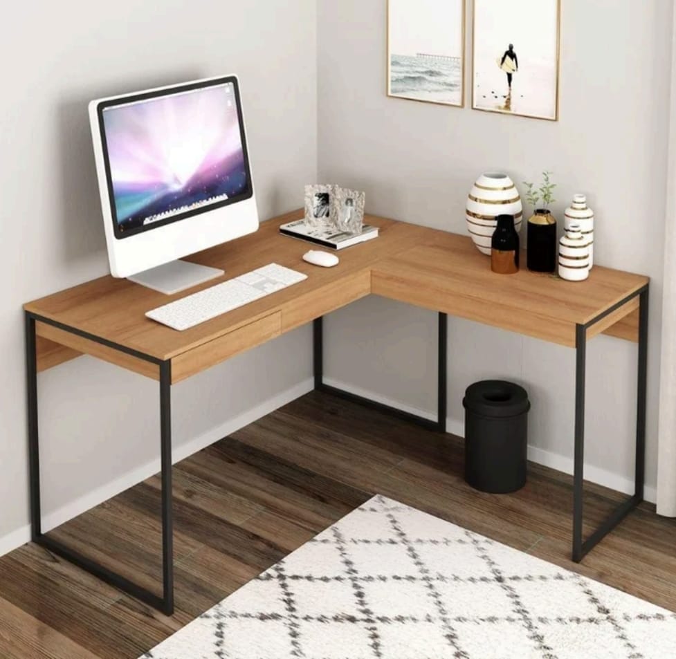 Wooden L-shaped desk with computer setup in a room with decor elements.
